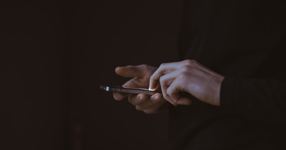 Silhouette of a person holding a smartphone at night