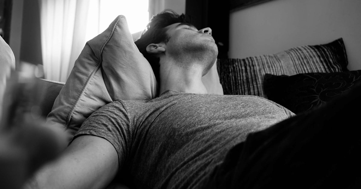 Grayscale photo of a man lying asleep in bed