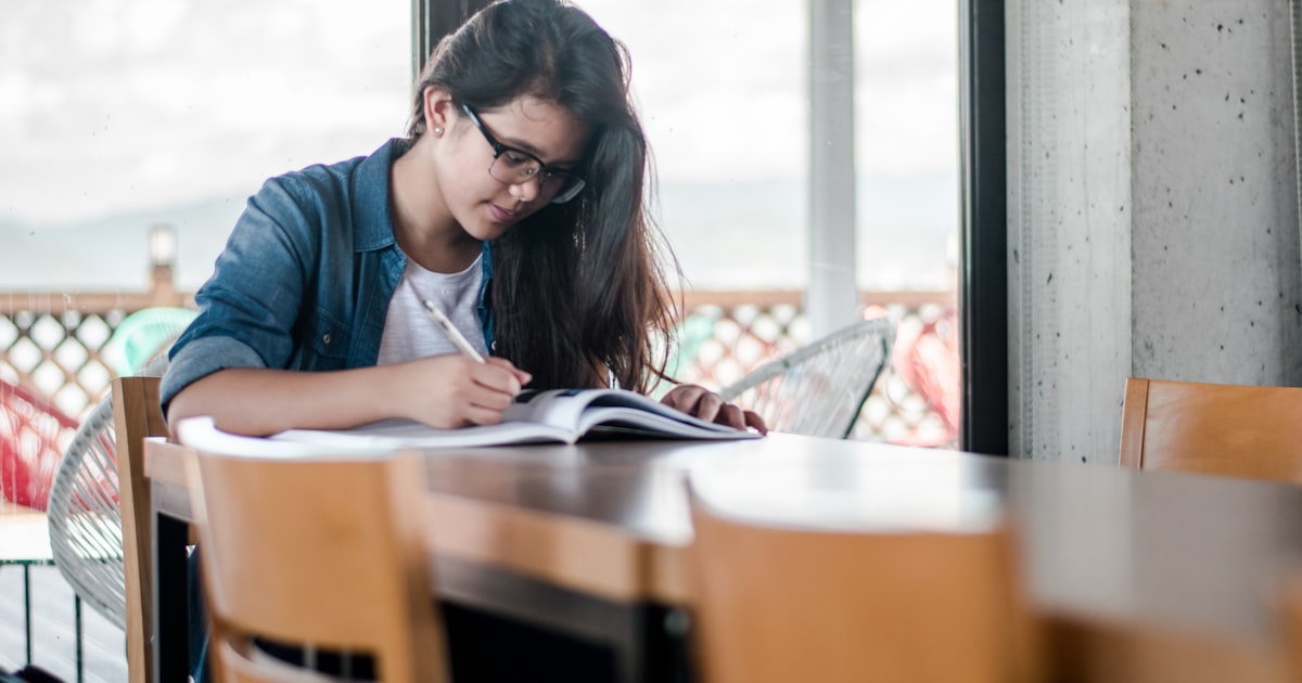 A woman writing notes in a book while studying