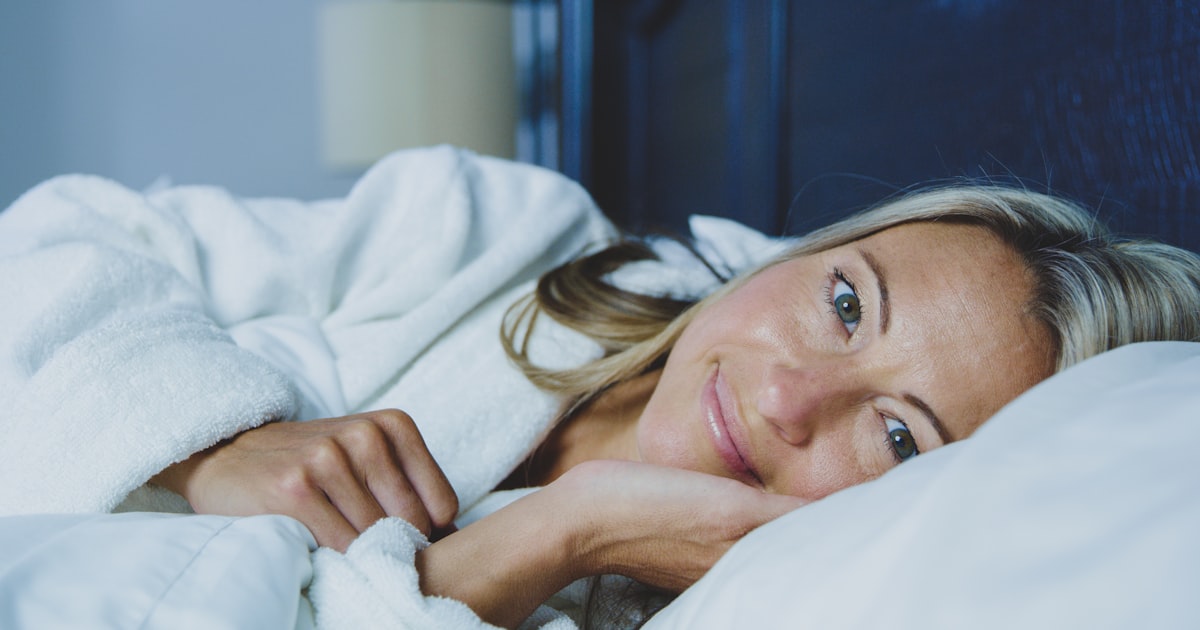 Person laying in bed under a cozy blanket