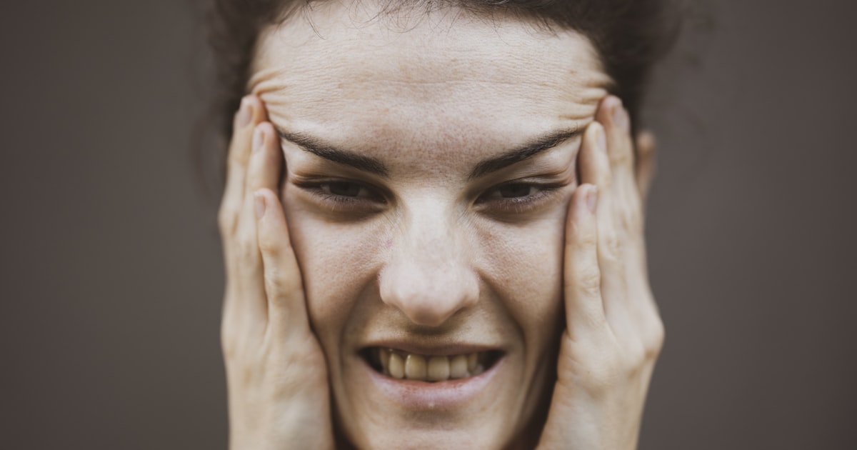 A woman holding the side of her face and jaw