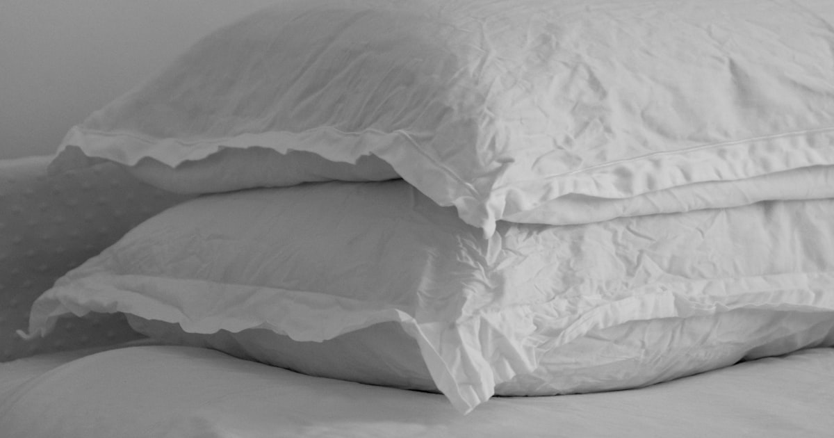 A white pillow on a neatly made bed