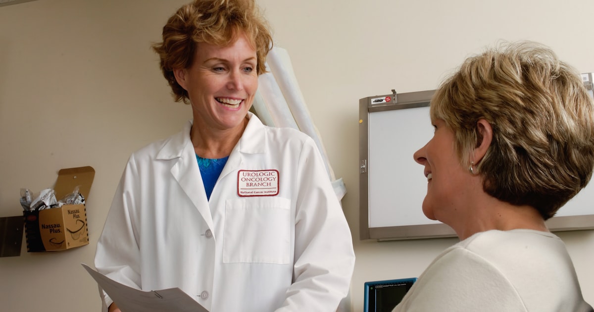 A clinician in a white coat working at a laptop