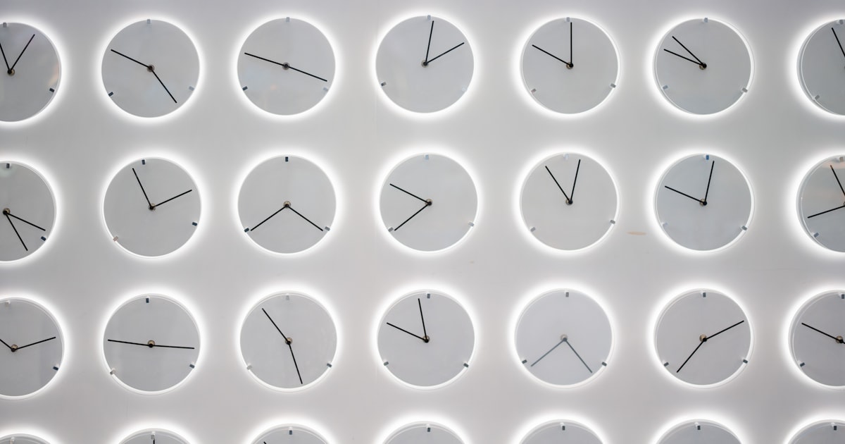 A white wall covered with many clocks