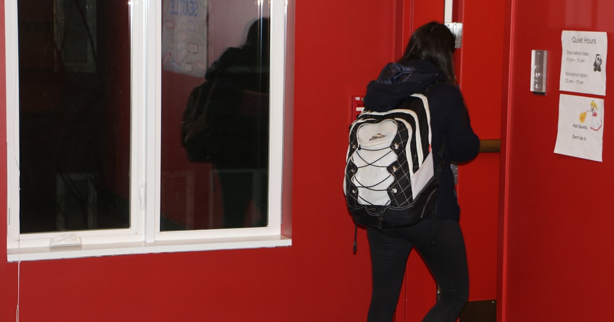 A student with a backpack entering a building