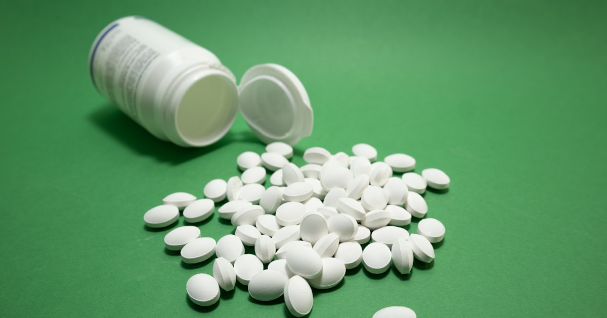 White pills spilled from an open supplement bottle